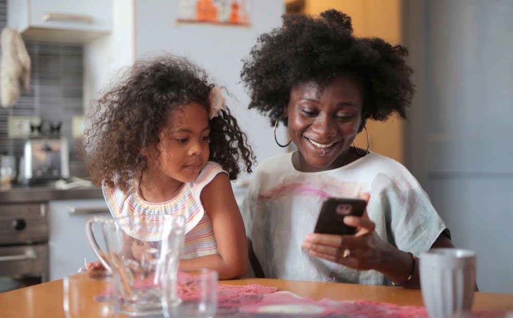 Parent and child looking at a phone together at the kitchen table