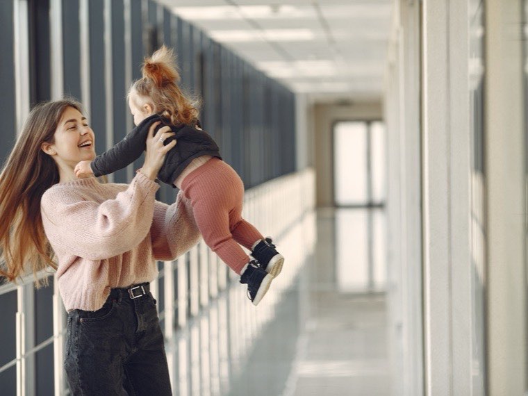 Au pair lifting a laughing toddler into the air
