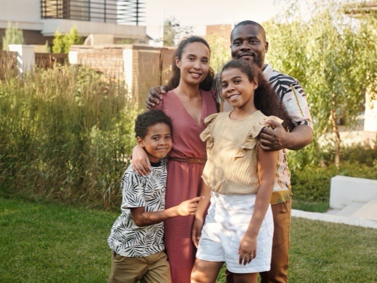 Host family of four standing together in their garden
