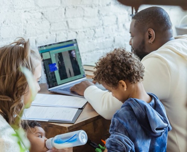Two parents and their children looking at a laptop together