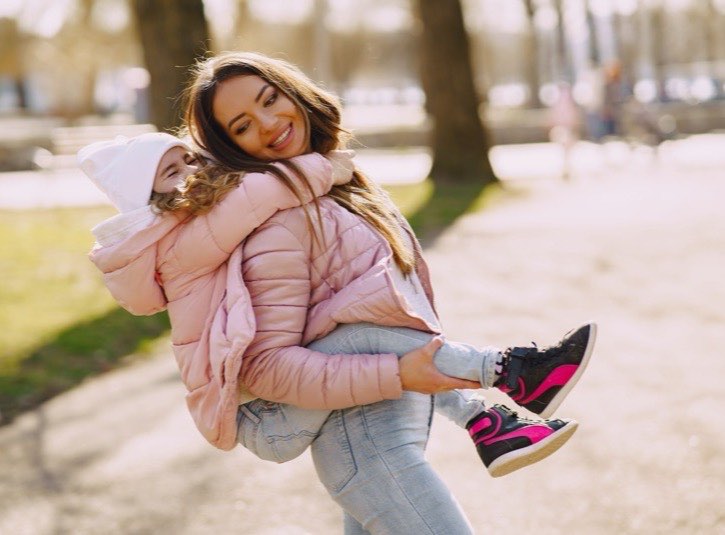 Au pair carrying a child on her back in a park
