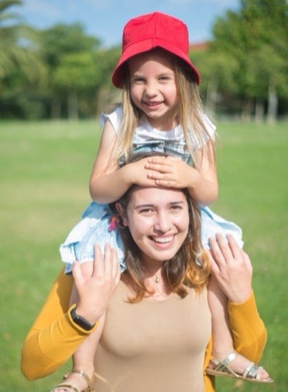 Au pair carrying a child on her shoulders in a park